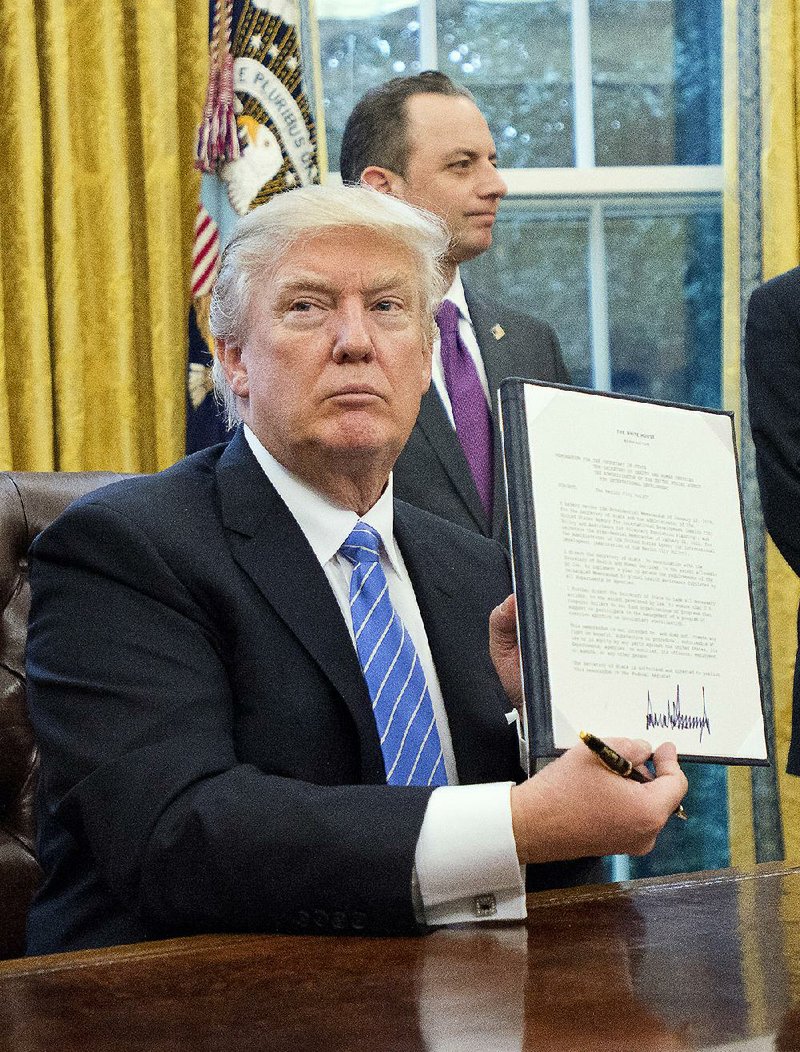 President Donald Trump on Monday holds up an executive order that reinstates what is known as the Mexico City Policy, a ban on providing federal money to international groups that perform abortions or discuss the option with patients.