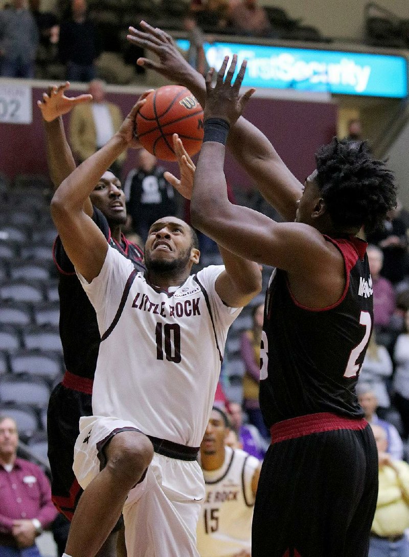 UALR forward Maurius Hill (center) drives between Troy defenders DeVon Walker (left) and Jordon Varnado in Monday night’s game at the Jack Stephens Center in Little Rock. Hill had nine points, but Varnado’s 25-point, 13-rebound outing was enough to power Troy past UALR 78-69.