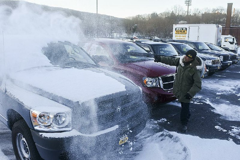 An employee at a vehicle-rental business in Pottsville, Pa., removes snows from automobiles in this  file photo. Americans are projected to return 3.36 million leased cars and trucks this year, creating a glut that is lowering prices for used vehicles.