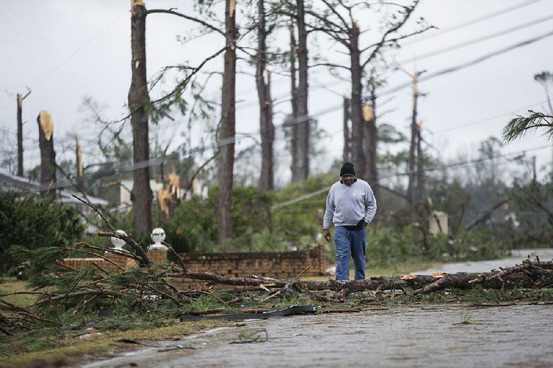 Mike Jones walks Monday through an Albany, Ga., neighborhood that was damaged by a tornado.