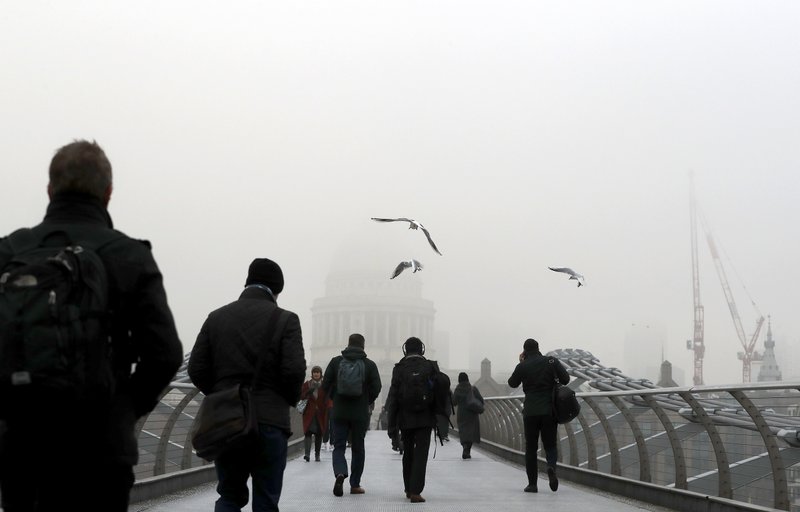 Pedestrians walk over the Millennium Bridge as fog shrouds St Paul's Cathedral in London, Monday, Jan. 23, 2017. Freezing fog covered the capital on Monday as cold weather conditions continued. 
