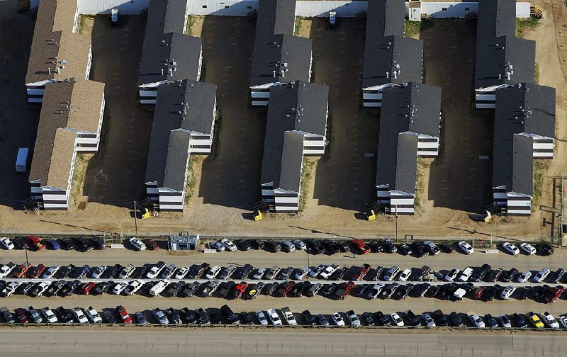 Cars fill a parking lot at a Syncrude Canada worker-housing camp at the Athabasca Oil Sands near Fort McMurray, Alberta, in this file photo. Rising oil prices have oil sands employees returning to work after two lean years. 