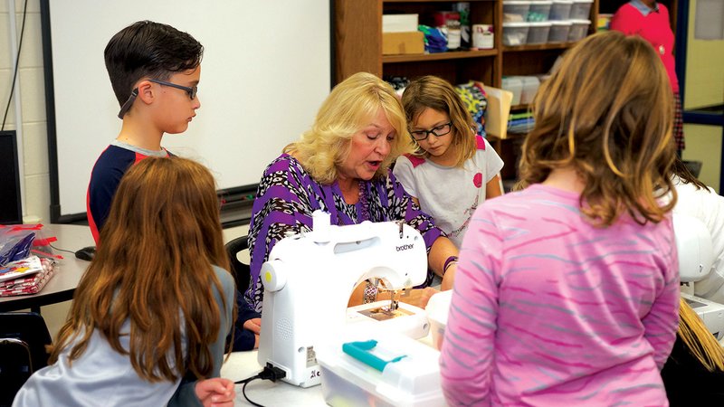Ward Central Elementary School third-grade teacher Lissa Monroe demonstrates sewing basics to Nathaniel Rodriguez-Maldonado, 9, at her right, and Erin Waters, 8, at Monore’s left, and others during Club Awesome, the school’s after-school program that covers academic tutoring and extracurricular enrichment opportunities.