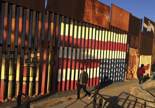 People pass graffiti along the border structure in Tijuana, Mexico, on Wednesday, Jan. 25, 2017. 