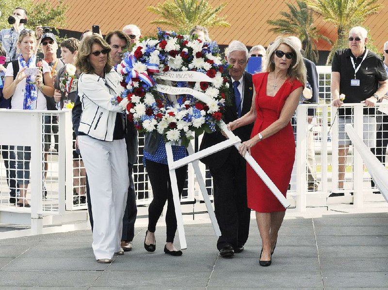 Sheryl Chaffee (from left), daughter of Roger Chaffee; Thad Altman, president of the Astronauts Memorial Foundation; Lowell Grissom, brother of Virgil Grissom; and Bonnie Baer, daughter of Ed White, carry a wreath to the base of the Space Mirror Memorial on Thursday at the Kennedy Space Center in Florida.