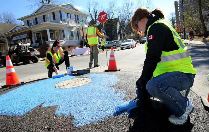Bonnie Adams (right) with Travel with Care and Rachel Schaffner, project coordinator for Fayetteville’s Sustainability Department, paint the interior of a new mini-roundabout Thursday at Spring Street and School Avenue. The mini-roundabout is a pilot project to exemplify the concept of tactical urbanism. The project is similar to the temporary crosswalk in front of the Walton Arts Center’s Nadine Baum Studios.