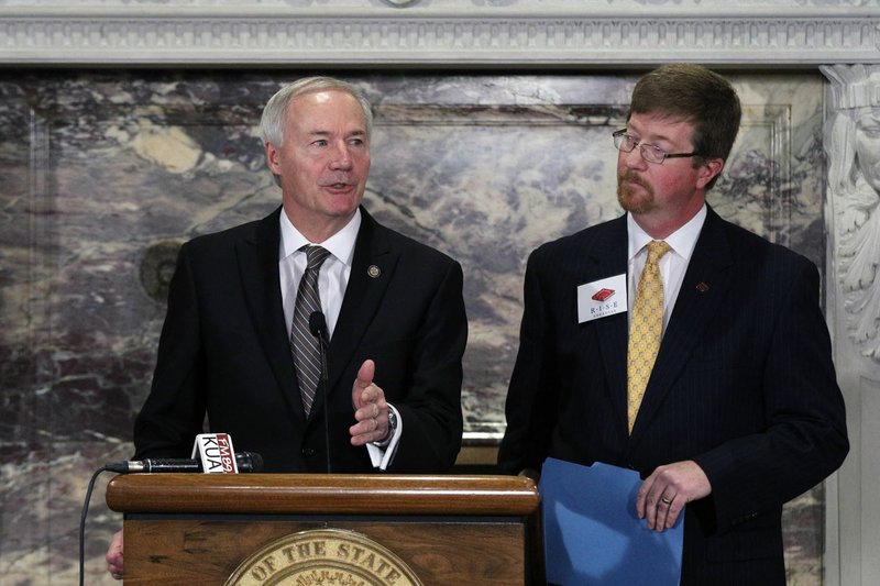 Gov. Asa Hutchinson (left), standing with Education Commissioner Johnny Key, speaks during an announcement Thursday of a statewide reading initiative.