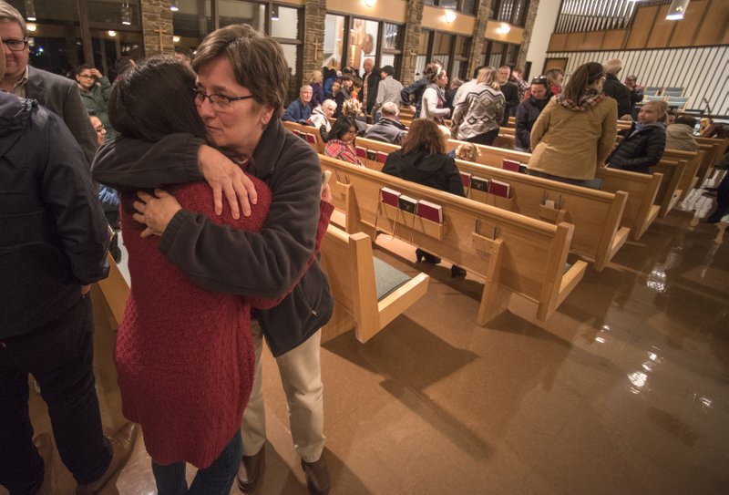 Mayra Esquivel of Springdale (left) hugs Susan Young of Fayetteville on Thursday after the Interfaith Vigil for Immigrant and Refugee Solidarity at the Good Shepherd’s Lutheran Church in Fayetteville. The event was organized in part by the Arkansas United Community Coalition to react more formally to this week’s presidential executive orders as well as discussions by the state Legislature on anti-immigrant legislation.