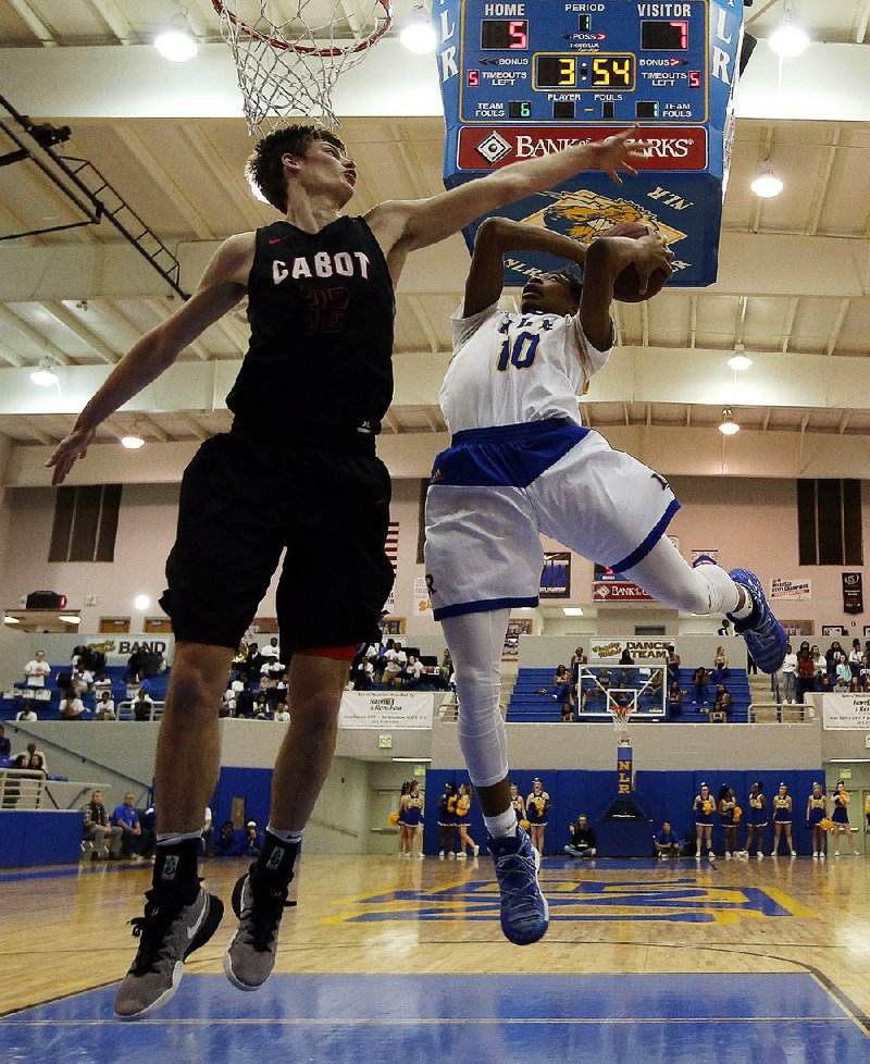 North Little Rock’s Collin Moore (10) drives to the basket as Cabot’s Matt Stanley tries to block the shot during the Charging Wildcats’ 67-62 overtime victory over the Panthers on Friday in North Little Rock.