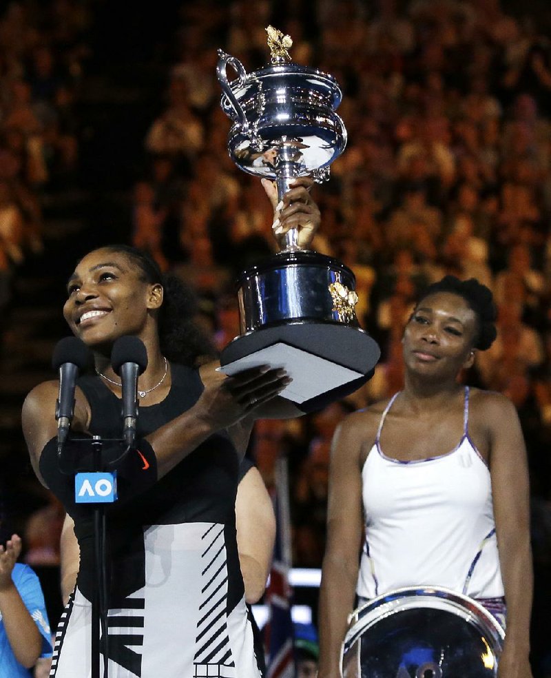 Serena Williams hoists the trophy after defeating her sister, Venus Williams (right), in the women’s singles final at the Australian Open on Saturday.