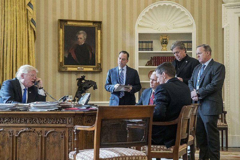 President Donald Trump speaks on the phone Saturday with Russian President Vladimir Putin as Chief of Staff Reince Priebus (center from left), Vice President Mike Pence, national security adviser Michael Flynn, senior adviser Steve Bannon and White House spokesman Sean Spicer gather in the Oval Office of the White House.