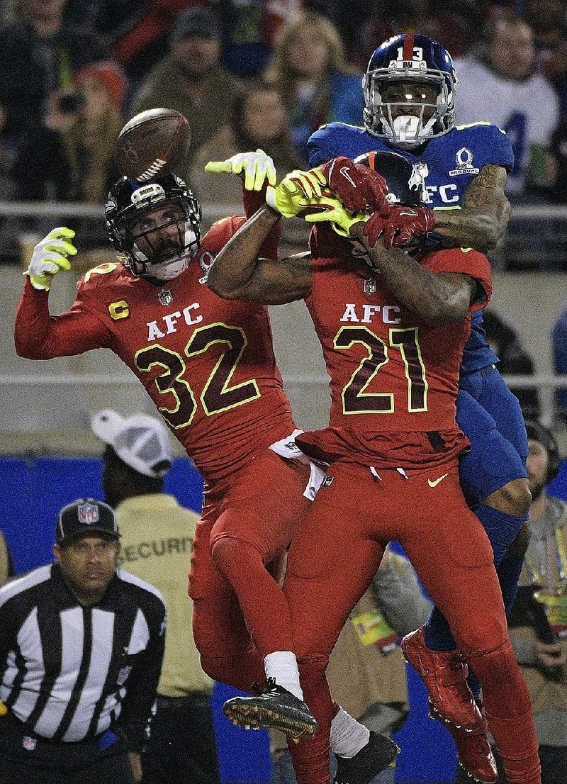 AFC cornerback Aqib Talib (21), of the Denver Broncos, and safety Eric Weddle (32), of the Baltimore Ravens, attempt to intercept a pass intended for NFC wide receiver Odell Beckham Jr., of the New York Giants, in the second half of the AFC’s 20-13 victory Sunday at Camping World Stadium in Orlando, Fla. The AFC defense intercepted two passes in the game, including one that sealed the victory.