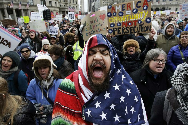 Izzy Berdan of Boston wears an American fl ag as he marches with other demonstrators during a rally Sunday in Boston against President Donald Trump’s order that restricts travel to the U.S.