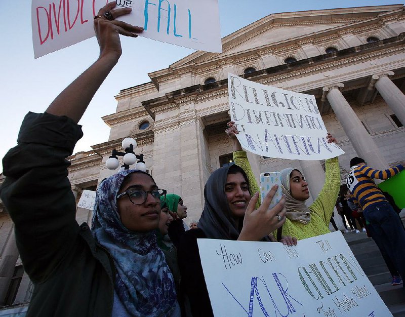 Anya Ali (from left), Arooba Ilyas and Roshaneh Ali, all of Little Rock, hold signs and listen to speakers during an immigration rally at the state Capitol on Sunday.