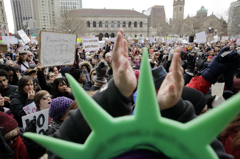 A demonstrator wears a Statue of Liberty hat and applauds during a rally against President Trump's order that restricts travel to the U.S., Sunday, Jan. 29, 2017, in Boston. Trump signed an executive order Friday that bans legal U.S. residents and visa-holders from seven Muslim-majority nations from entering the U.S. for 90 days and puts an indefinite hold on a program resettling Syrian refugees. (AP Photo/Steven Senne)