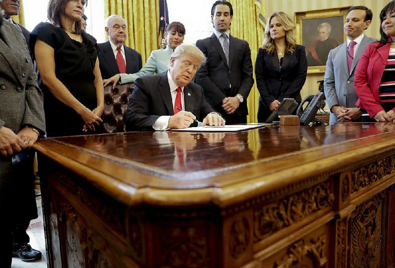 President Donald Trump, joined by small-business leaders at the White House on Monday, signs an executive order intended to cut regulations on businesses.