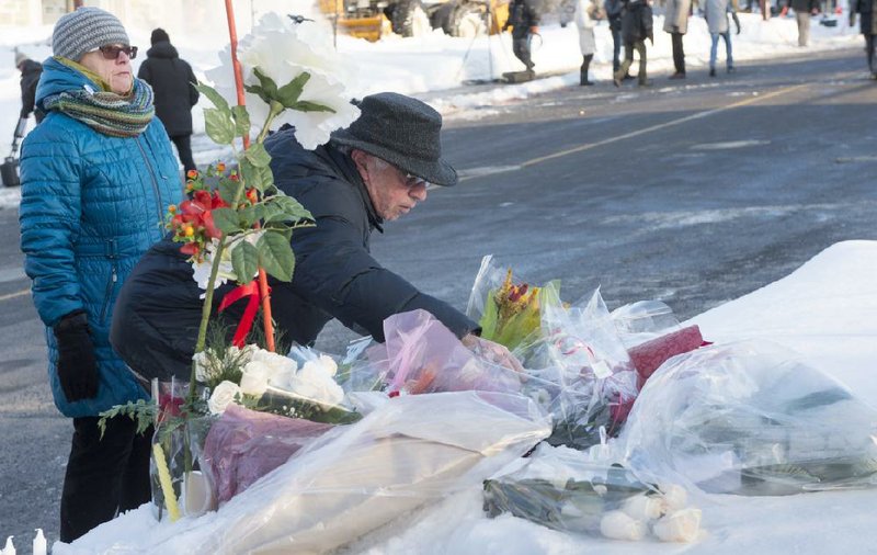 People place flowers Monday near a Quebec City mosque where a shooting Sunday night left several people dead.
