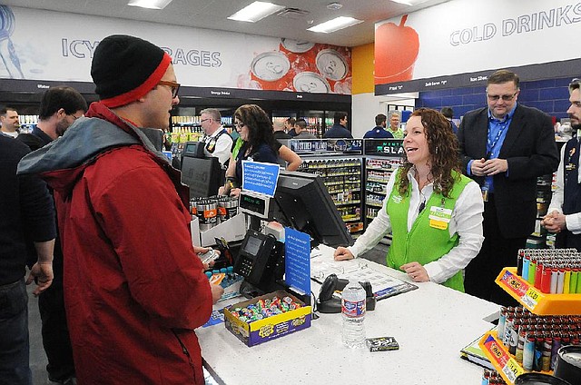 Cashier Kendall Stewart helps customer John Craft on Tuesday at a new Wal-Mart convenience store in Rogers.