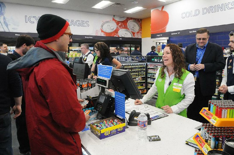 Cashier Kendall Stewart helps customer John Craft on Tuesday at a new Wal-Mart convenience store in Rogers.