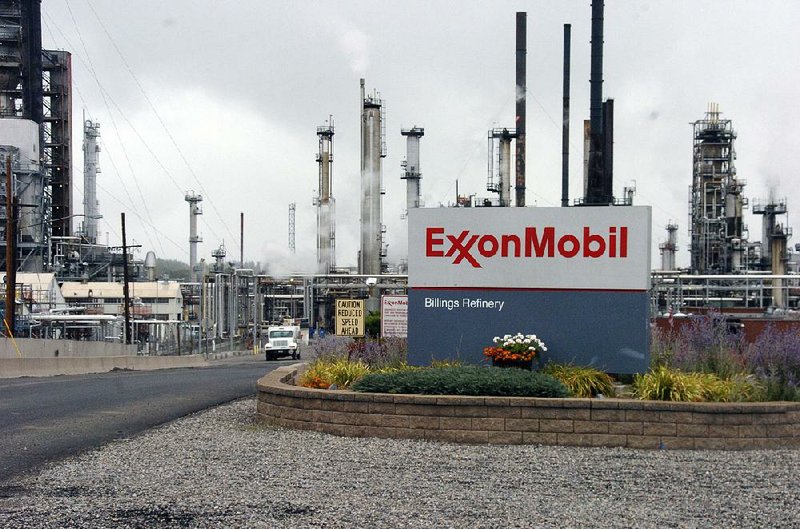 Steam rises from stacks at Exxon Mobil’s refi nery in Billings, Mont., in this file photo. Exxon on Tuesday reported net income of $1.68 billion in the fourth quarter, its smallest quarterly profit since 1999