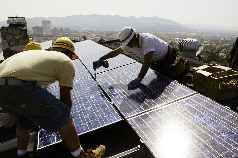 California Green Design workers install solar panels on a house in Glendale, Calif., in this file photo. Solar and wind industry leaders say rural areas are benefi ting from the expansion of clean energy.