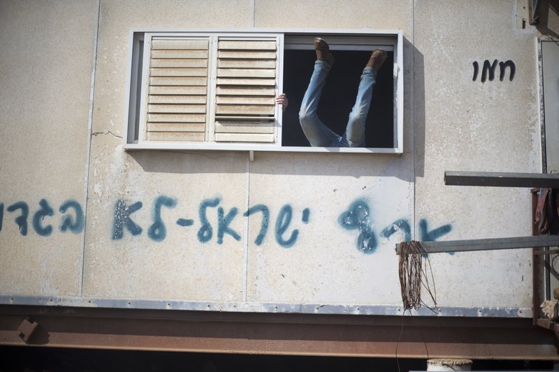 A settler jumps into a trailer in Amona outpost in the West Bank, Wednesday, Feb. 1, 2017. Israeli forces have begun evacuating a controversial settlement Amona, which is the largest of about 100 unauthorized outposts erected in the West Bank without permission but generally tolerated by the Israeli government. 
