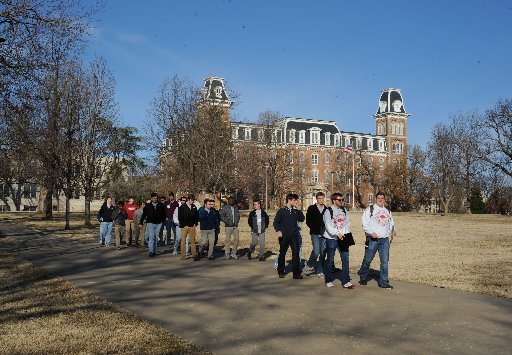 A crowd walks Saturday, Feb. 13, 2016, past Old Main and the University of Arkansas campus in Fayetteville.