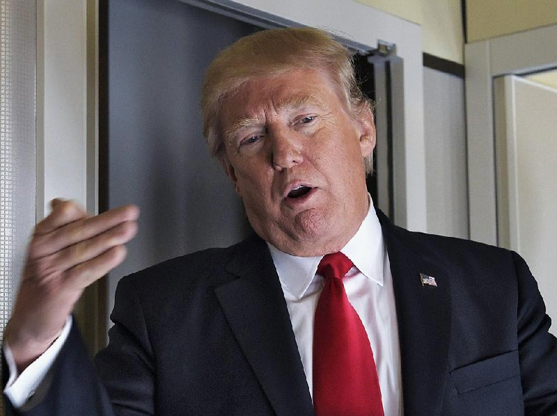 President Donald Trump talks to reporters Friday aboard Air Force One on his way to spend the weekend at his Mar-a-Lago resort in south Florida after a busy two weeks in Washington.