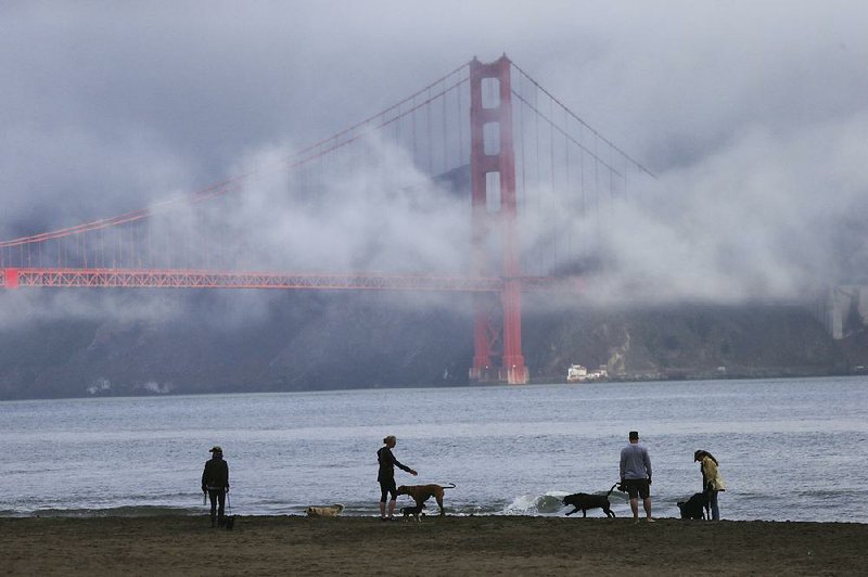 Fog forms around the Golden Gate Bridge in 2013 as people let their dogs roam along East Beach in Golden Gate National Recreation Area.