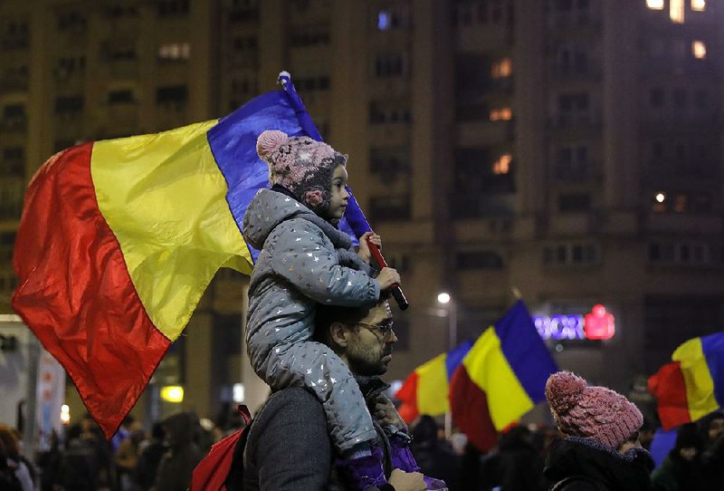 A child carries a Romanian national flag during a demonstration over a decree to decriminalize official misconduct in Bucharest, Romania, on Sunday.