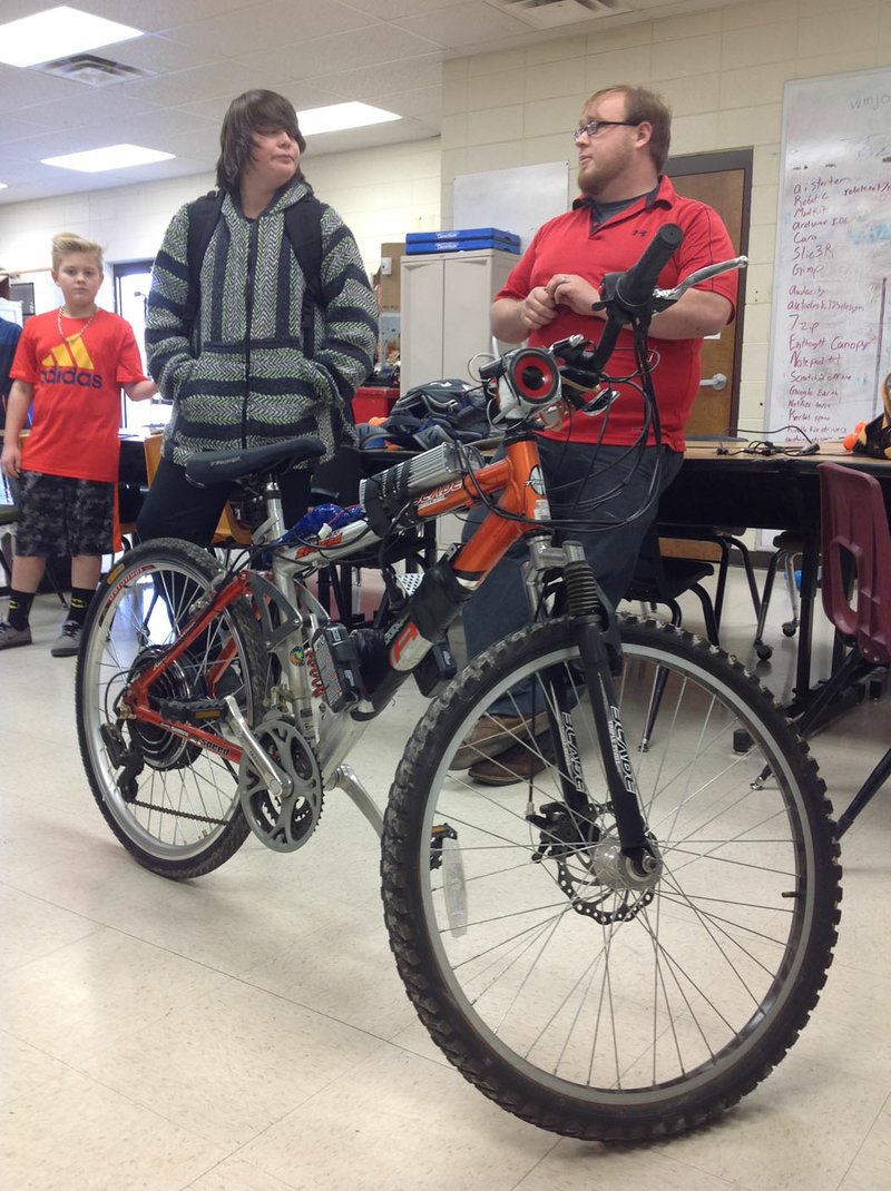 Blake Matthews (right), a science and technology teacher at Washington Junior High School, and eighth-grader Spencer Stevens, 14, stand behind an electric bicycle Spencer and other students assembled last month in Bentonville. About a dozen of Matthews&#8217; students worked on the project in their spare time before and during school for about a week last month. They worked on it in groups whenever those groups had the time, Matthews said.
