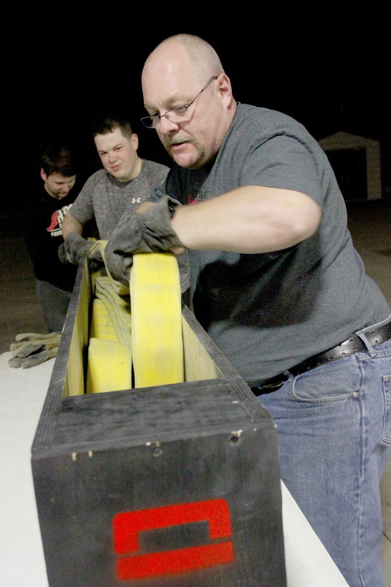 LYNN KUTTER ENTERPRISE-LEADER Farmington firefighter Chaz Birdsong practices loading a 200-foot water line with firefighters A.J. Jones and Kyle Martin. In this photo, firefighters are loading the line using a method called the triple layer load. They have been testing different methods to decide which load they like the best and is the most efficient for fighting fires.