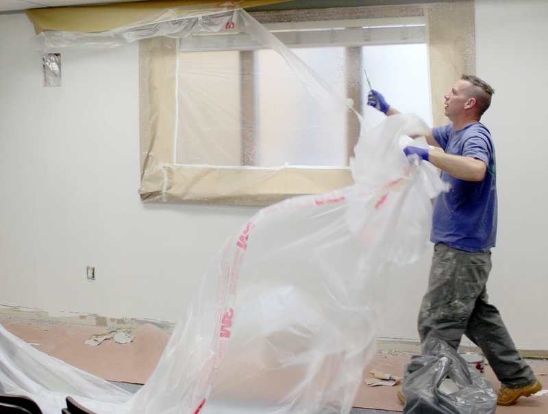 Keith Bryant/The Weekly Vista Bella Vista Fire Department Battalion Chief Robert Hamilton tears plastic off the ceiling after a long day of painting in the Bella Vista Fire Department&#8217;s training room.