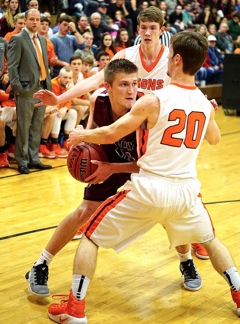 Photo by Randy Moll After rebounding a missed shot, Gentry&#8217;s Austin Morris is boxed in by Gravette players Andrew Miller and Camron Johnson during play in Gravette on Friday, Feb. 3, 2017.