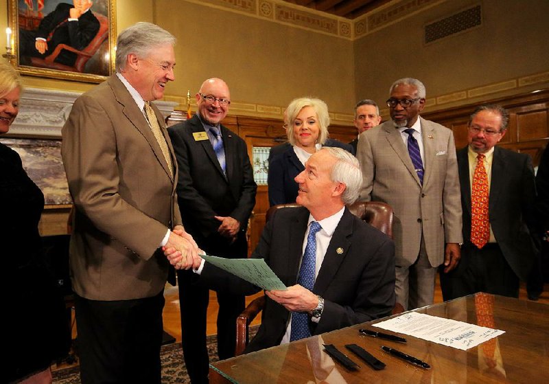Gov. Asa Hutchinson congratulates Rep. Mark Lowery, R-Maumelle, after signing the new higher-education funding formula Wednesday at the Capitol.
