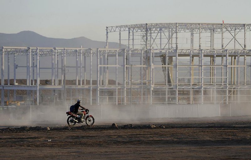 A worker rides past an unfinished building at the Ford production plant construction site near San Luis Potosi, Mexico, on Jan. 4, the day after Ford announced it was canceling plans to finish construction of the plant. 