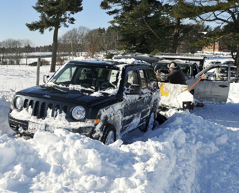 Jim McGrath tries to free his vehicle from a snowbank Friday in Wrentham, Mass.