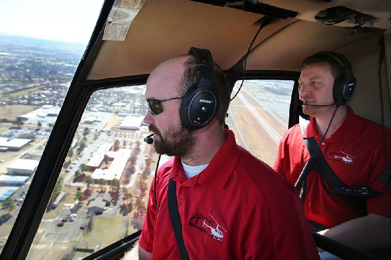 Camron McAhren (right) owner of Arkansas Helicopters, flies with pilot Kyle Flynn over Springdale. The company offers a variety of traditional aerial services as well as special flights like taking couples up for Valentine’s Day. 