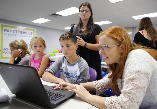 Alissa Benard looks on as Juli (cq) Johnson (from right), English Language Arts and Social Studies teacher at Fayetteville Virtual Academy, reviews the computer access with Maddox Benard, a seventh grade student, his sisters Indie, a second grade student, and Ava, a fifth grade student at the Academy, Wednesday, August 17, 2016, at the charter school on the first day of classes for the Fayetteville Public Schools's traditional calendar schools.