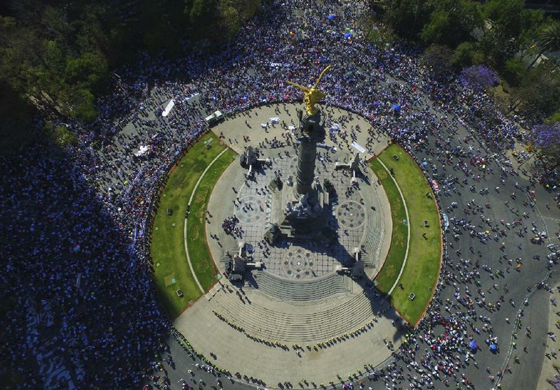 Thousands of demonstrators gather around the Angel of Independence monument Sunday in Mexico City during a march demanding respect for Mexico and its migrants in the face of perceived hostility from the administration of U.S. President Donald Trump.