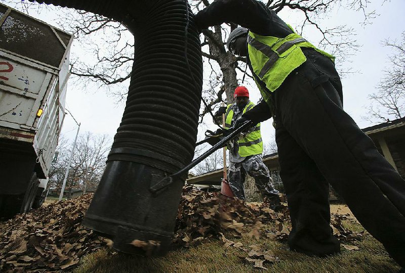 Corey Couch (left) and Brian Wilson of the North Little Rock Sanitation Department vacuum up leaves on Lakeshore Place in the Lakewood area of North Little Rock in this file photo.
