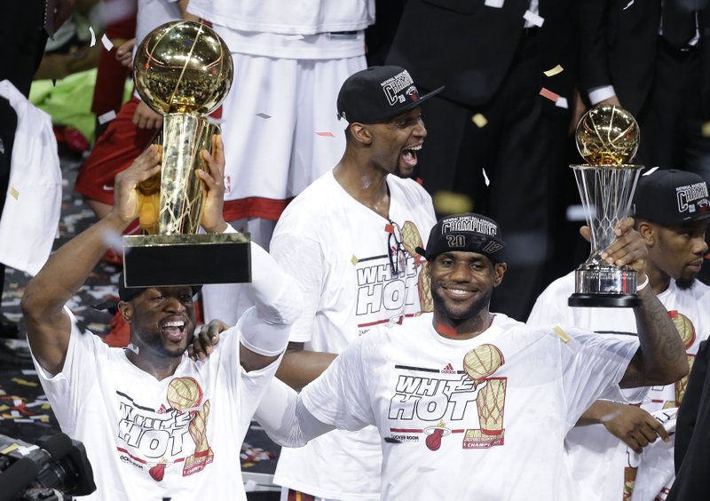 FILE - In this June 21, 2013, file photo, the Miami Heat's Dwyane Wade, left, holds the Larry O'Brien NBA Championship Trophy as LeBron James holds his Bill Russell NBA Finals Most Valuable Player Award and Chris Bosh, top, reacts after Game 7 of the NBA basketball championship against the San Antonio Spurs, in Miami. There have been superteams that found winning formulas, like Miami when James and Bosh joined Wade. 