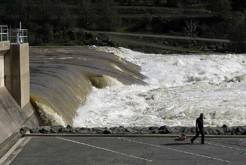 The Feather River flows downstream Tuesday from the damaged dam at Oroville, Calif., where crews worked to shore up eroded areas with sandbags, concrete blocks and boulders. 