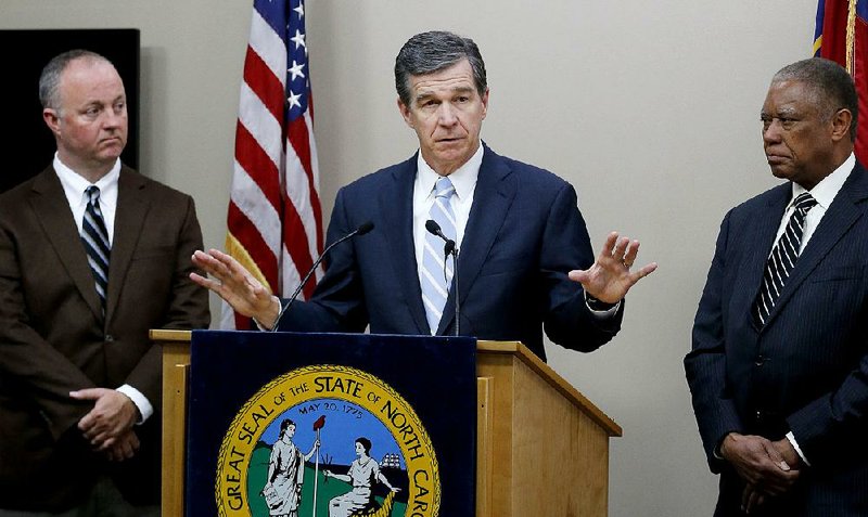 North Carolina Gov. Roy Cooper (center) addresses a news conference Tuesday in Raleigh, N.C., with state House Democratic leader Darren Jackson (left) and state Senate Democratic leader Dan Blue.