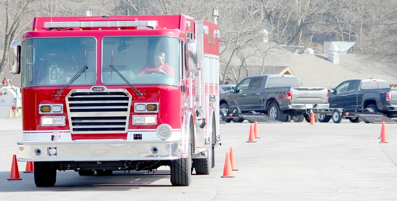 Keith Bryant/The Weekly Vista Bentonville firefighter Oscar Olvera shimmies the firetruck between cones during the driver-operator tests.