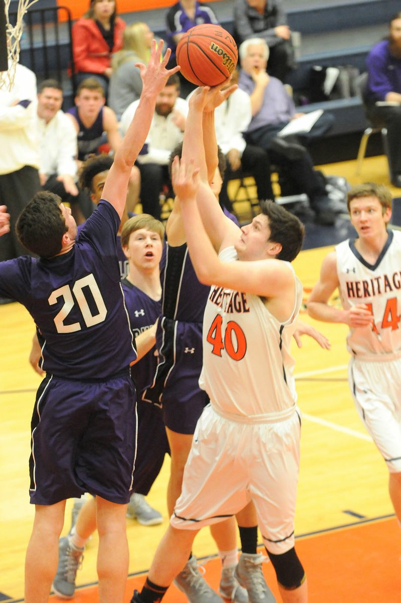 NWA Democrat-Gazette/FLIP PUTTHOFF  Nick Lowery (40) of Rogers Heritage attempts to shoot over Fayetteville’s Caleb Finney (20) on Tuesday at Rogers Heritage.