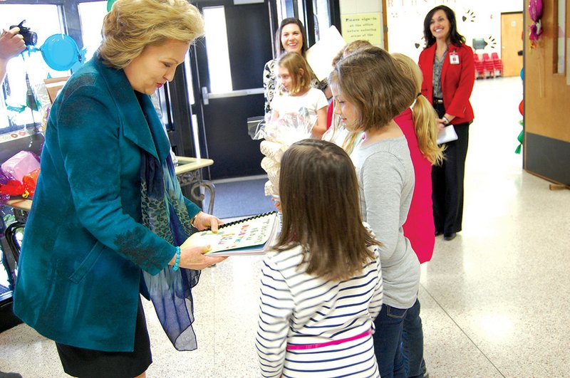Arkansas first lady Susan Hutchinson accepts a handmade gift from Northside Elementary School students Ava Berryhill, left, and Piper Brown. Hutchinson was the guest speaker at the school’s One School, One Book program, which unveiled The Chocolate Touch as this year’s schoolwide book.