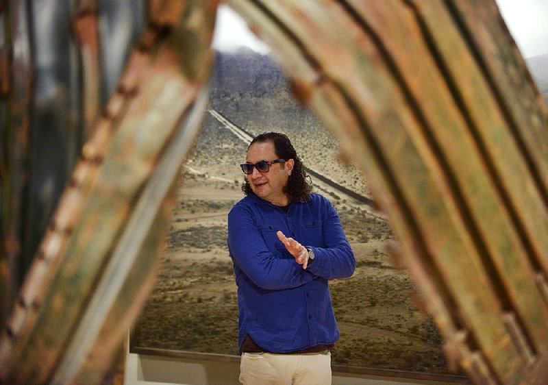 Guillermo Galindo, co-collaborator of the first full-scale bilingual exhibit at Crystal Bridges Museum of American Art in Bentonville, stands Thursday near his piece The Angel Exterminador (Exterminating Angel), which was sculpted from a piece of the border wall.
