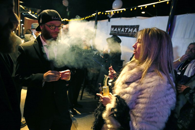 FILE - In this Dec. 31, 2013 file photo, partygoers smoke marijuana during a Prohibition-era themed New Year's Eve invite-only party celebrating the start of retail pot sales, at a bar in Denver. Colorado is on the brink of becoming the first state with licensed pot clubs. 