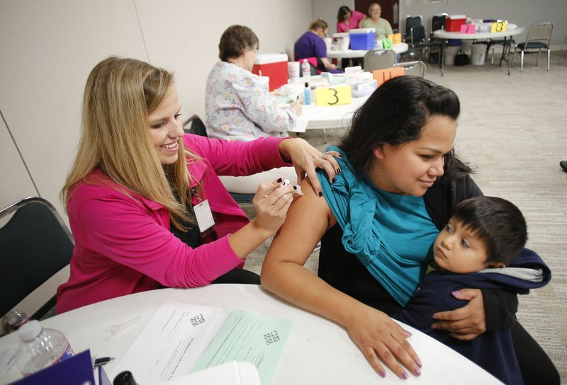 Ana Rivera holds onto her son Ivan, 4, as she receives a shot from Stefanie Ryan, R.N., with the Arkansas Department of Health, Thursday, October 13, 2016, at a Arkansas Department Health MMR vaccination and flu shot clinic at the Jones Center in Springdale. The vaccination clinic is in response to a mumps outbreak that the health department reported to be nearly 500 people this week.
